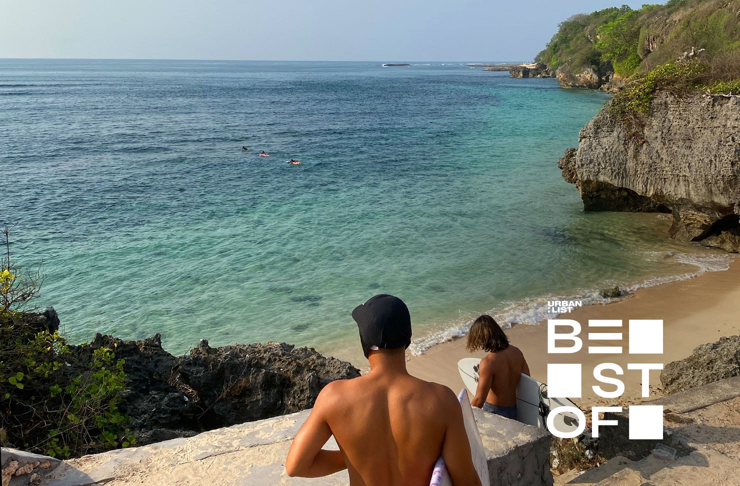 two people carrying surfboards walking down stairs to a beach